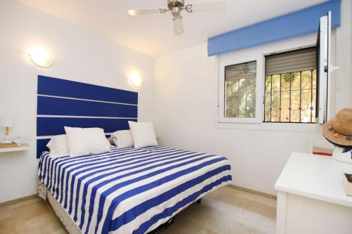 1 dormitorio con cama de rayas azul y blanco en Appartement la Cala de Mijas toegang tot strand, en Mijas