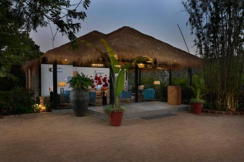 a hut with a grass roof and some plants at LaRiSa Resort & Spa, Ashwem in Mandrem