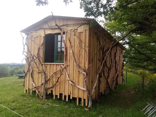 a wooden shed with a window and a tree at Ferme de la Luciole in Champs Sur Tarentaine