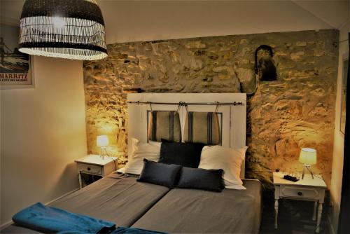 ein Schlafzimmer mit einem Bett mit einer Steinmauer in der Unterkunft Chambres d'hôtes dessine-moi un chemin in Sauvelade