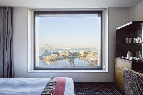 a bedroom with a large window with a view of a harbor at New Otani Inn Yokohama Premium in Yokohama