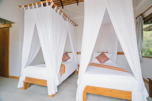 two beds in a room with white drapes at Bor Saen Pool Villa in Bor Saen