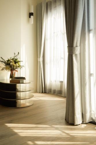 a room with white curtains and a table with flowers at Hotel Sapin in Pom Prap