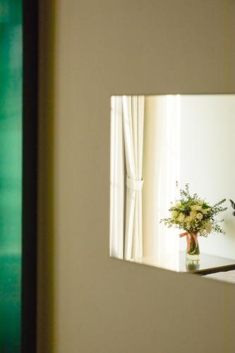 a mirror with a vase of flowers on a table at Hotel Sapin in Pom Prap