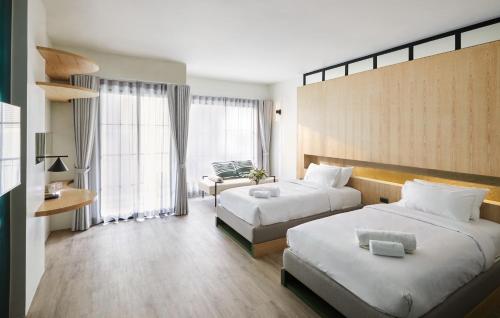 een hotelkamer met 2 bedden en een raam bij Hotel Sapin in Pom Prap