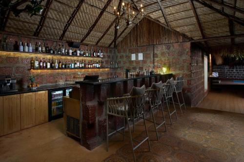 a bar with a row of stools in a room at LaRiSa Resort & Spa, Ashwem in Mandrem