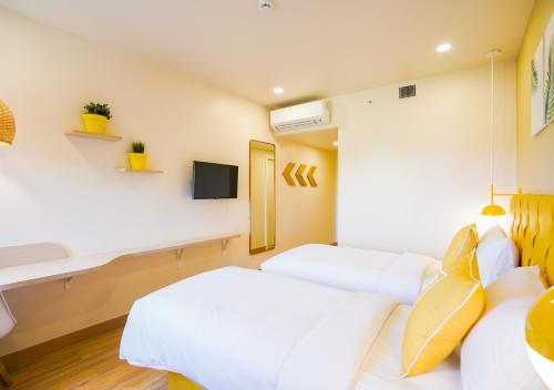 a bedroom with two white beds and a tv at Bloom Hotel - Bengaluru Airport in Devanahalli-Bangalore