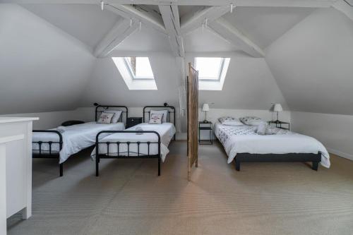 a attic room with three beds and two windows at La Grande Maison Gannat in Gannat