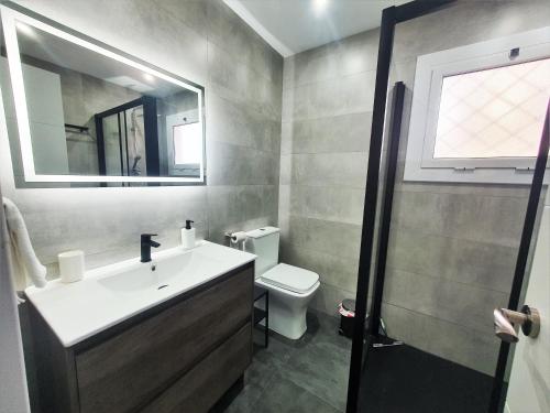 Un baño con lavabo, inodoro y espejo. en Apartamento nuevo a 5 Minutos de la Playa, en Platja d'Aro
