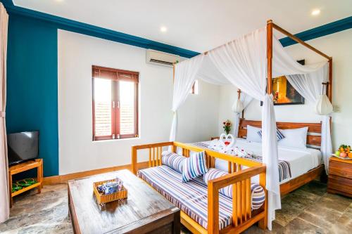 a bedroom with a canopy bed and a couch at Relax Garden Boutique Villa Hoi An in Hoi An