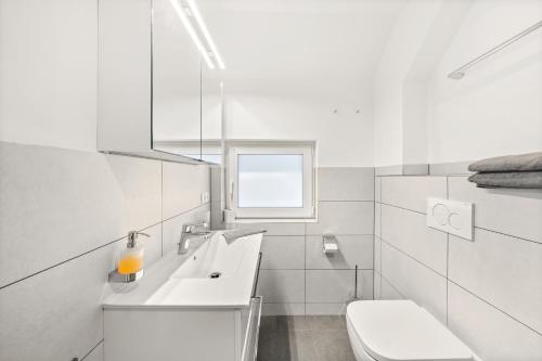 a white bathroom with a sink and a toilet at Hallstatt Lakeside Top 5 - Zimmer mit Balkon in Hallstatt