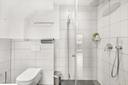 a white bathroom with a shower and a toilet at Hallstatt Lakeside Top 5 - Zimmer mit Balkon in Hallstatt