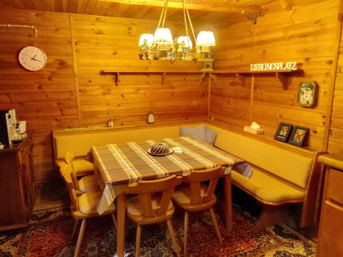 ein Esszimmer mit einem Tisch, Bänken und einer Uhr in der Unterkunft Hütte Waldesruh in Kaltenberg