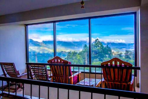 a balcony with three chairs and a large window at Awinco Haputale in Haputale