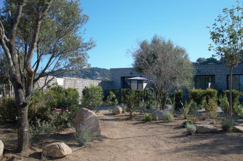 um jardim com pedras e árvores em frente a um edifício em N°1 - Maison T2 em Ajaccio