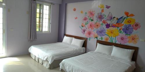 two beds in a room with a painting on the wall at Vineyard Guest House in Taitung City