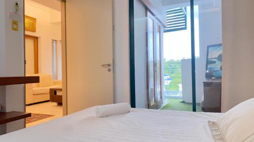 a bedroom with a white bed and a balcony at Peninsula Residence All Suite Hotel in Kuala Lumpur