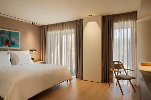 a hotel room with a large bed and a chair at Dusit Suites Hotel Athens in Athens