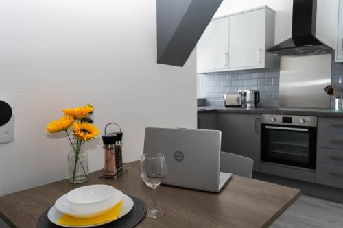 una cocina con mesa de madera y ordenador portátil. en Sky Apartments, en Bradford