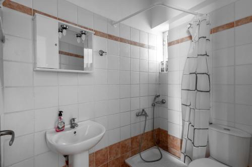 a white bathroom with a sink and a toilet at Elia mini suites 5 in Larisa