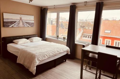 Schlafzimmer mit einem Bett, einem Schreibtisch und Fenstern in der Unterkunft O-Mer Oostende in Ostende