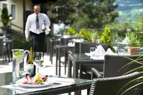 a table with a plate of food and a bottle of wine at Gartenhotel Völser Hof - Adults Only in Fiè