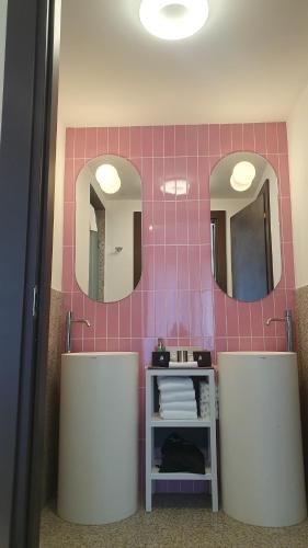 a bathroom with two sinks and two mirrors at OMAMA Hotel in Aosta