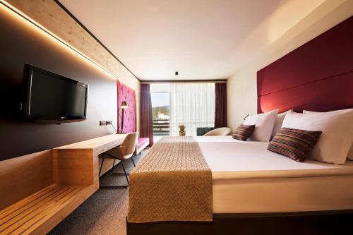 a hotel room with a bed and a flat screen tv at Rikli Balance Hotel – Sava Hotels & Resorts in Bled