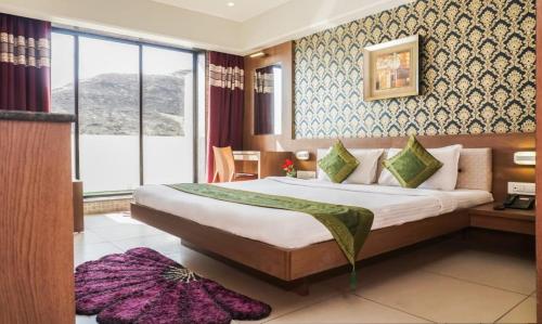 a hotel room with a bed and a large window at Shri Vitthal Mangalam Satara in Satara
