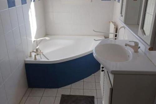 La salle de bains est pourvue d'une baignoire bleue et blanche ainsi que d'un lavabo. dans l'établissement La Maison des Palombes, à Francheville