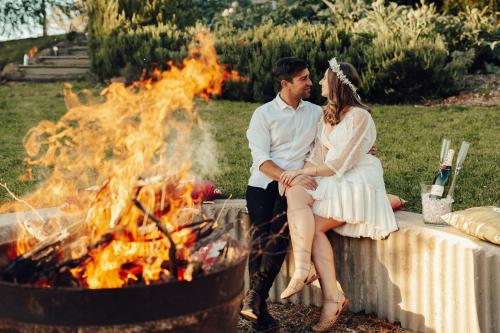 a bride and groom sitting next to a fire at 17pounds Country Estate & Aqua Wellness Retreat in Bullarto