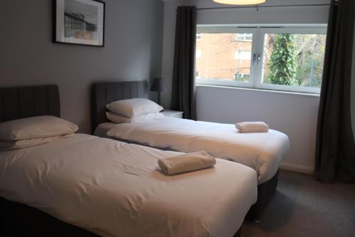two beds in a room with a window at Century Wharf Apartments by Urban Space in Cardiff