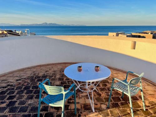 2 sillas y una mesa en un patio con vistas al océano en Villa Sa Torre Blanca, en Colonia de San Pedro