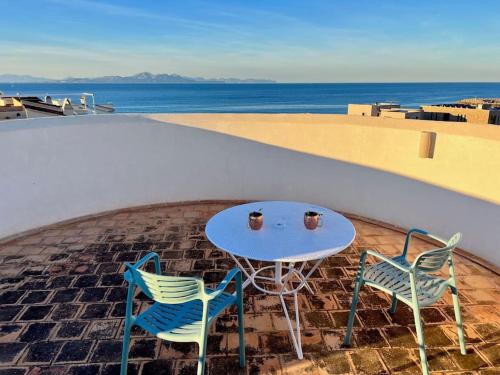 two chairs and a table on a patio with the ocean at Villa Sa Torre Blanca in Colonia de Sant Pere