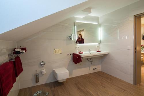 a bathroom with a sink and a person in the mirror at Hotel Garni Jägerhof in Sigmaringen