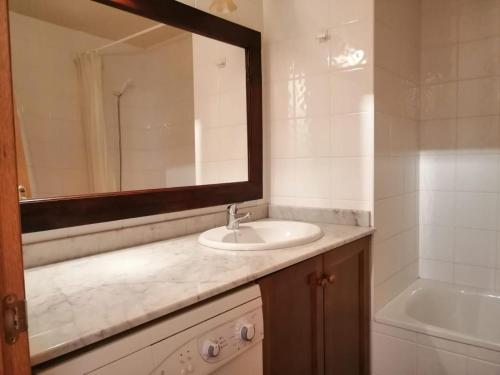 La salle de bains est pourvue d'un lavabo, d'un miroir et d'une baignoire. dans l'établissement Apartamento muy espacioso y luminoso Erta 5, à Pla de l'Ermita