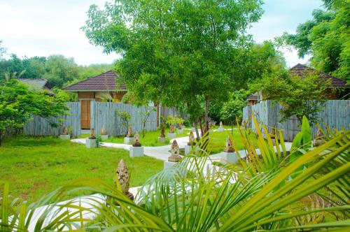 a backyard with a fence and a yard with plants at Villa Samalas Resort and Restaurant in Gili Meno