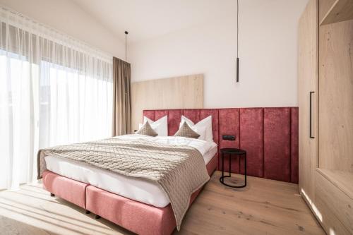 a bedroom with a large bed with a red headboard at Die Zillertalerin in Uderns