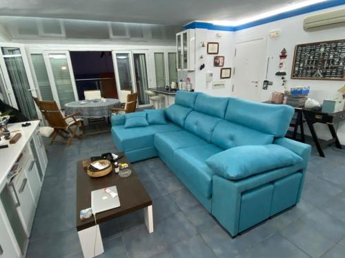 salon z niebieską kanapą i stołem w obiekcie Ático con vistas al mar w mieście Balerma