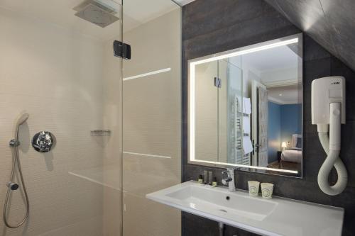 La salle de bains est pourvue d'un lavabo et d'une douche avec un miroir. dans l'établissement Grand Hôtel Malher, à Paris