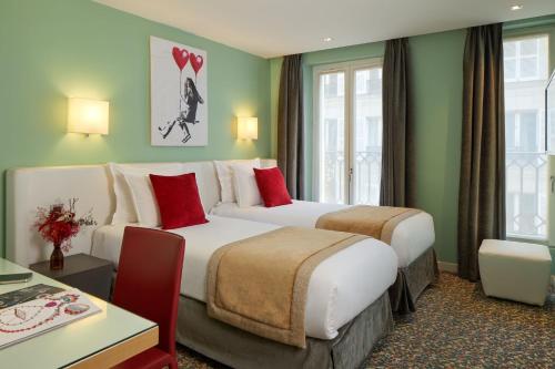 Habitación de hotel con 2 camas con almohadas rojas en Grand Hôtel Malher en París