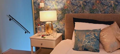 a bedroom with a bed with a lamp on a night stand at The Newport Lodge - incl 3h Wellness & use Ebikes & breakfast in Nieuwpoort