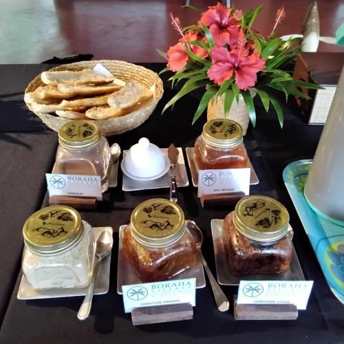 a table with jars of honey and a bowl of bread at Boraha Village Ecolodge in Sainte Marie