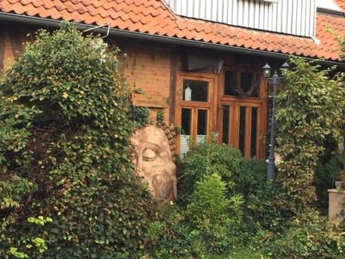 uma casa com uma escultura de um rosto na frente dela em Schöne Gartenwohnung im Klosterdorf Mariensee em Neustadt am Rübenberge