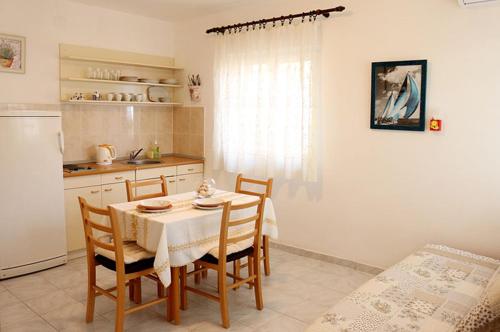 eine Küche mit einem Tisch und Stühlen sowie einem Kühlschrank in der Unterkunft Apartmani Diego in Sveta Nedelja