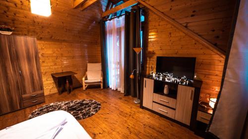 Habitación con cama, TV y escritorio. en Pinewood Cabin en Brasov