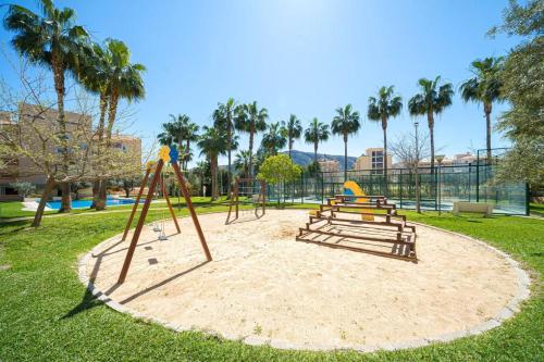 Ein Park mit einem Spielplatz mit Bänken und einer Rutsche in der Unterkunft Alborada Golf 3BD in Albir