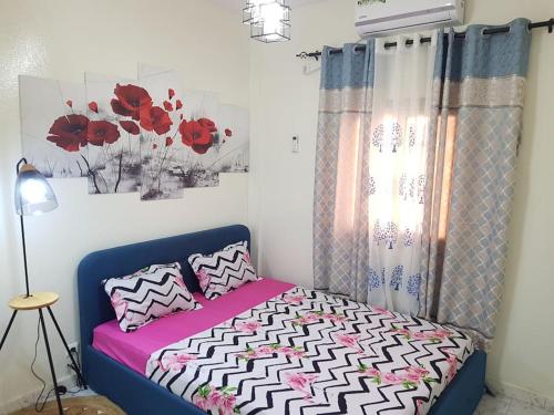 1 dormitorio con 1 cama con flores rojas en la pared en Charmant F3, 2 chambres + salon à Yoff plage bceao, en Dakar