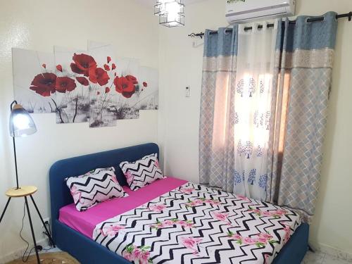 a bedroom with a bed with red flowers on the wall at Charmant F3, 2 chambres + salon à Yoff plage bceao in Dakar
