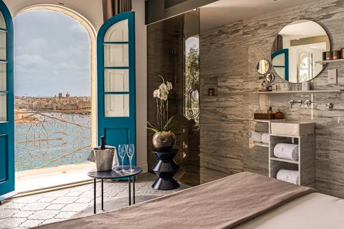 a bedroom with a large window and a bathroom at Iniala Harbour House in Valletta